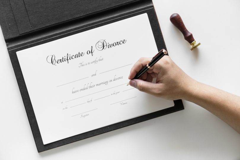 A Certificate of divorce with a hand and a pen