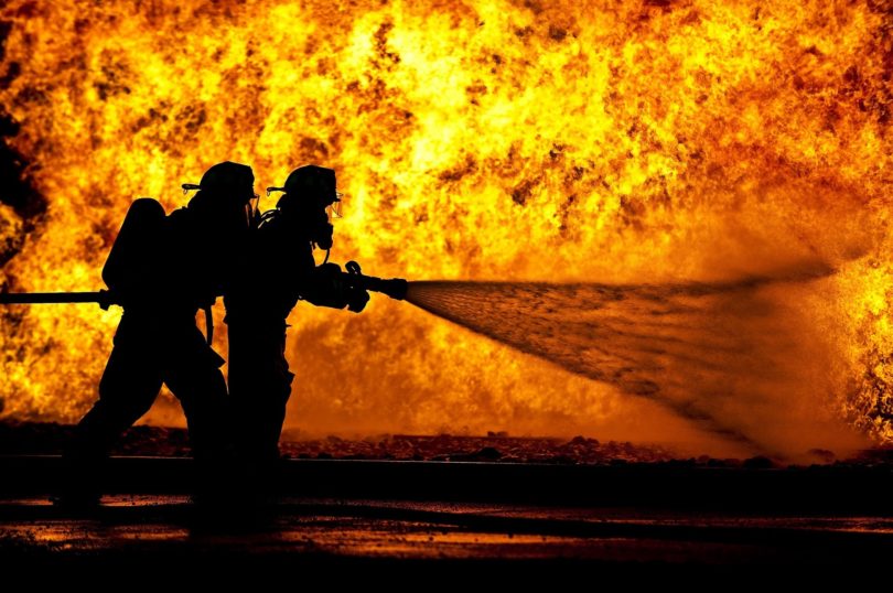 Two fire persons spreading water on the fire